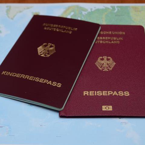 Foto: Symbolbild - ein Reisepass und ein Kinderreisepass liegen auf einer Weltkarte