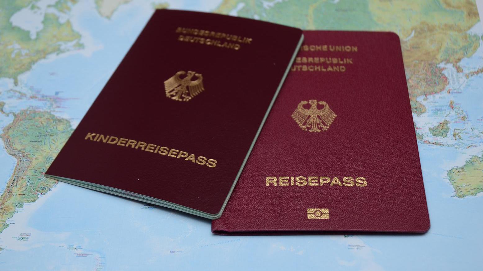 Foto: Symbolbild - ein Reisepass und ein Kinderreisepass liegen auf einer Weltkarte