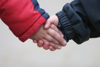 Auf dem Foto sind zwei Kinderhände Hand in Hand zu sehen