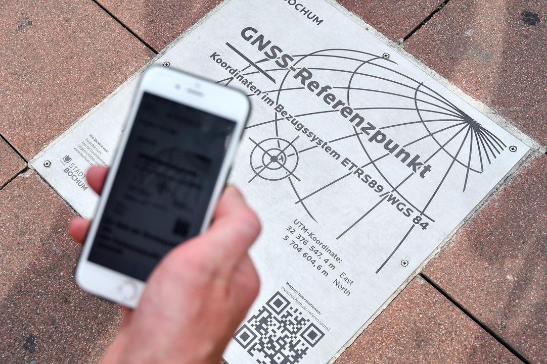 Eine Hand mit Handy über dem Referenzpunkt