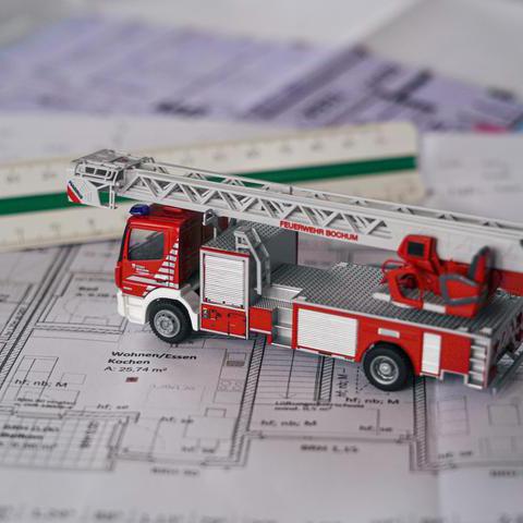 Bauzeichnung mit Lineal und einem Modell-Feuerwehrfahrzeug