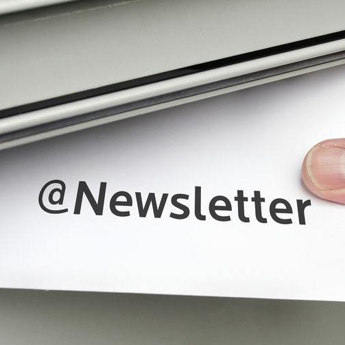 Symbolbild zum Thema Newsletter - eine Hand wirft einen Umschlag in einen Briefkasten