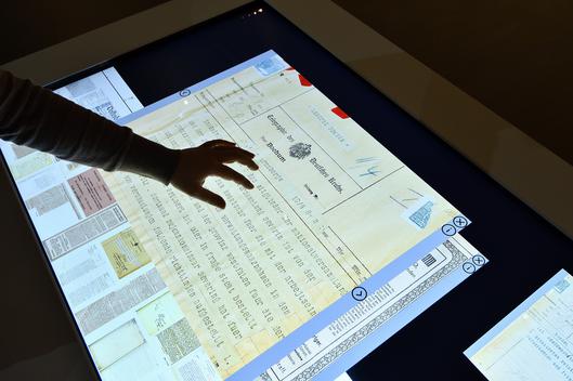Über einen interaktiven Bildschirm werden bei einer Ausstellung im Stadtarchiv Informationen präsentiert.