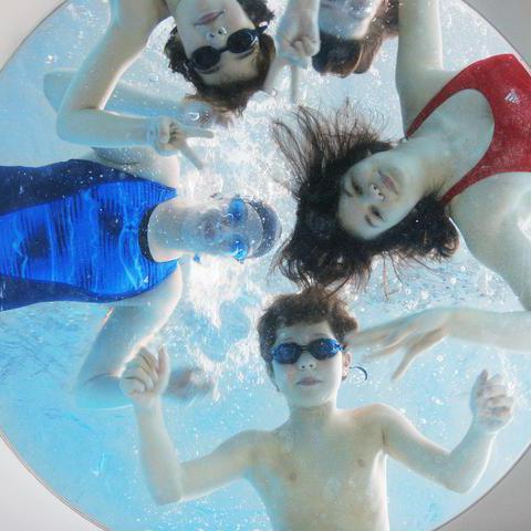 Vier Kinder im Schwimmbad schauen durch ein Fenster