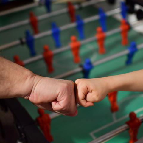 Zwei Hände vor einem Kicker-Spieltisch - Symbolfoto Kinder- und Jugendfreizeithaus