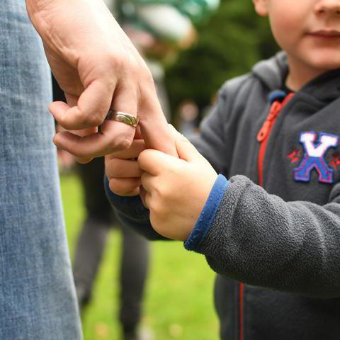 Symbolfoto zum Thema Erziehung: Ein Kind hält die Hand seines Vaters.