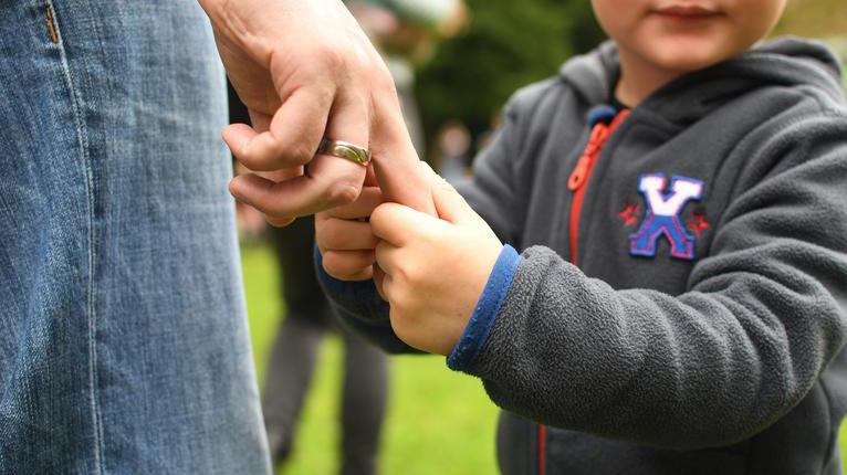 Symbolfoto zum Thema Erziehung: Ein Kind hält die Hand seines Vaters.