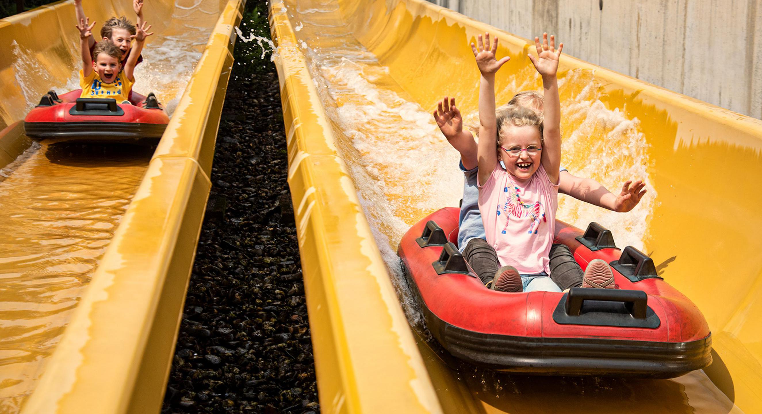 Kinder in Booten auf einer Wasserrutsche