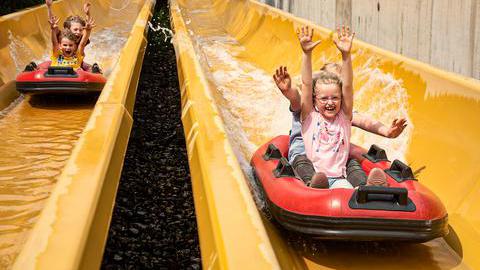 Kinder in Booten auf einer Wasserrutsche