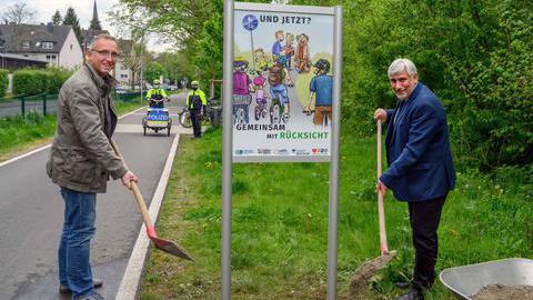 Es zeigt den Bezirksbürgermeister Marc Gräf und den Bochumer Polizeipräsidenten Jörg Lukat, die ein Schild an der Springorumtrasse in Dahlhausen für ein faires Miteinander auf Geh- und Radwegen aufstellen.