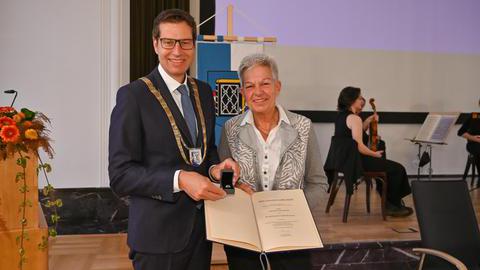 Oberbürgermeister Thomas Eiskirch und Frau Gabriele Ankenbrand präsentieren den Ehrenring und die dazugehörige Verleihungsurkunde