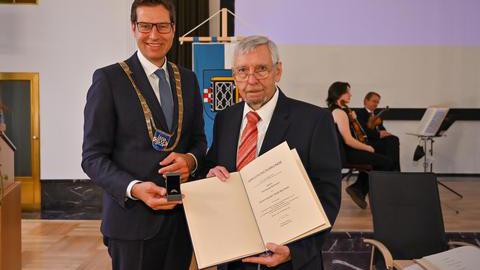Oberbürgermeister Thomas Eiskirch und Wolfgang Breßlein präsentieren den verliehenen Ehrenring mitsamt der Verlehungsurkunde.