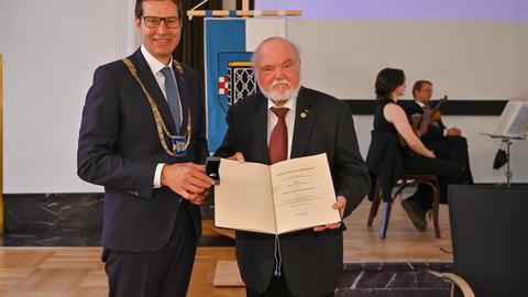 Klaus-Peter Hülder und Oberbürgermeister Thomas Eiskirch präsentieren den Ehrenring und die zugehörige Verleihungsurkunde 