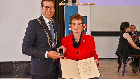 Erika Post und Oberbürgermeister Thomas Eiskirch präsentieren den verliehenen Ehrenring und die zugehörige Urkunde