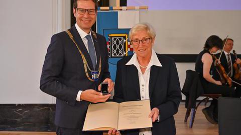Erika Stahl und Oberbürgermeister Thomas Eiskirch präsentieren den verliehenen Ehrenring mitsamt der zugehörigen Urkunde