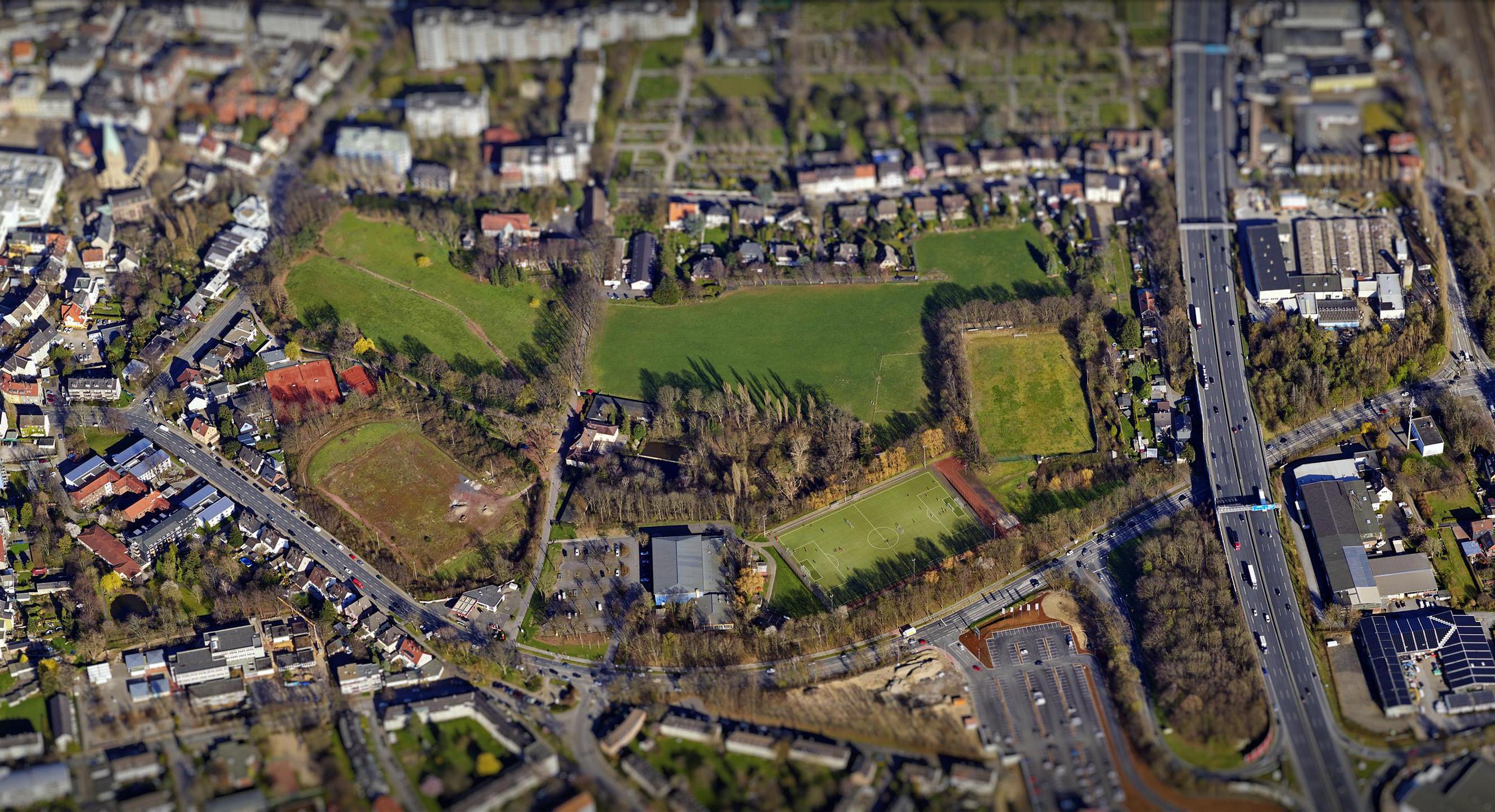Unten im Bild ist die Berliner Straße, oben die Straße An der Papenburg zu erkennen. Links verläuft von oben nach unten die BAB 40. Das Plangebiet in der Mitte besteht aus landwirtschaftlich genutzten Grünflächen und Sportplätzen.