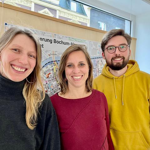 Portrait des Teams des Stadtteilbüros vor einer Karte des Soziale-Stadt-Gebiets. Von links nach rechts: Frau Fürup, Frau Triglone, Herr Schedler
