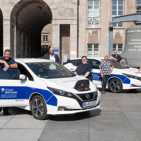Mitarbeiterinnen und Mitarbeiter des Ordnungsamtes zeigen die neuen elektrischen Autos des Ordnungsamtes. 