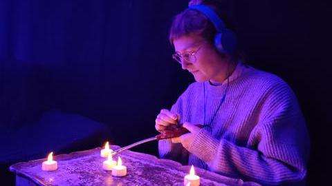 Das Bild zeigt eine Frau, die durch LED-Teelichter visuelle Geräuschquellen erzeugt.