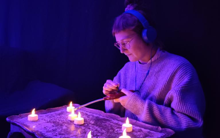 Das Bild zeigt eine Frau, die durch LED-Teelichter visuelle Geräuschquellen erzeugt.