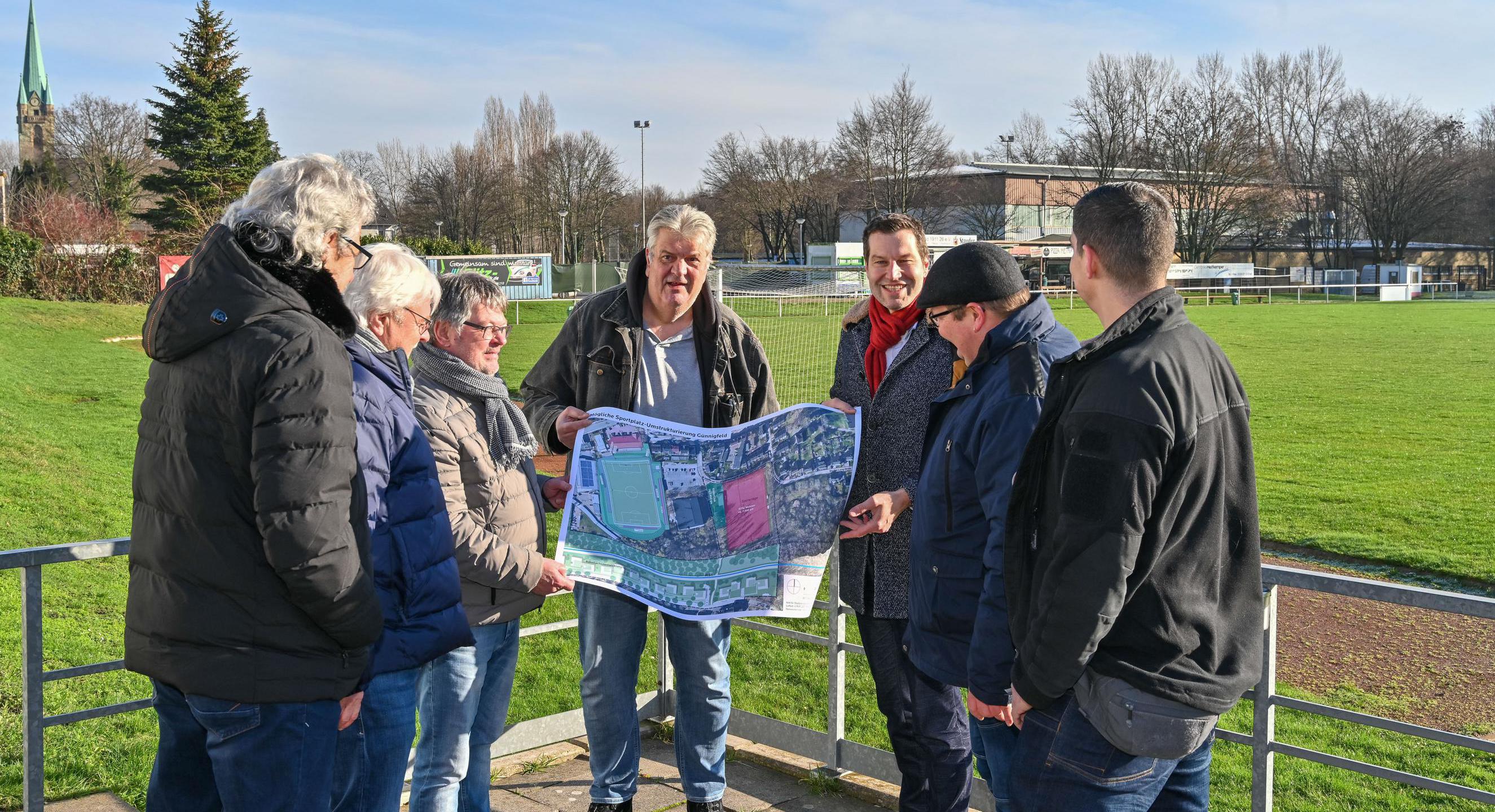 Frank Scheffler als Vorstand des VfB Günnigfeld und Oberbürgermeister Thomas Eiskirch schauen sich am 18.01.2023 gemeinsam mit Vereinsmitgliedern und Vertretern der Politik in Bochum-Günnigfeld Pläne für eine mögliche Umgestaltung der dortigen Sportplätze an.