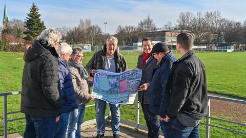 Frank Scheffler als Vorstand des VfB Günnigfeld und Oberbürgermeister Thomas Eiskirch schauen sich am 18.01.2023 gemeinsam mit Vereinsmitgliedern und Vertretern der Politik in Bochum-Günnigfeld Pläne für eine mögliche Umgestaltung der dortigen Sportplätze an.