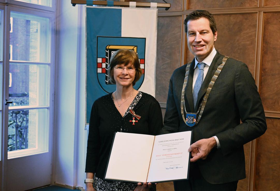 Oberbürgermeister Thomas Eiskirch übergibt das Bundesverdienstkreuz an Carmen Lumma.