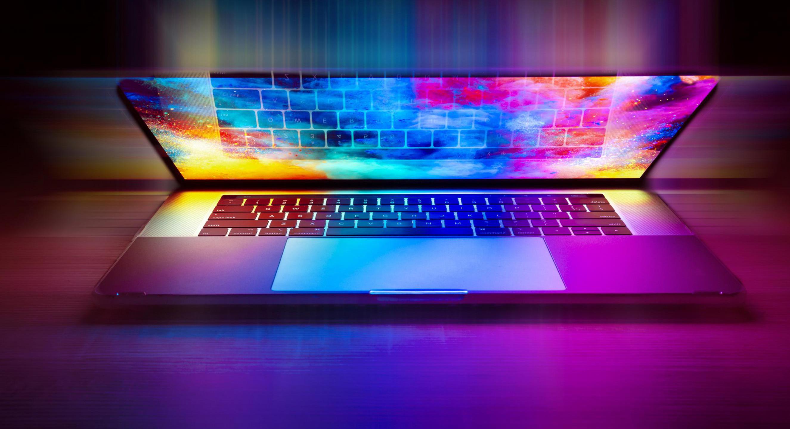 Ein halb aufgeklappte Laptop, auf dessen Bildschirm ein bunter Desktop zu sehen ist, dessen Farben gelb, grün, blau und lila das gesamte Bild erhellen.