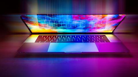 Ein halb aufgeklappte Laptop, auf dessen Bildschirm ein bunter Desktop zu sehen ist, dessen Farben gelb, grün, blau und lila das gesamte Bild erhellen.