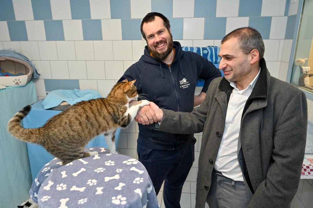Kater Alfred besiegelt mit seiner Pfote die Kooperation zwischen Julian Behrmann stellvertretend für das Bochumer Tierheim und Meheddiz Gürle stellvertretend für die Stadtbücherei Bochum