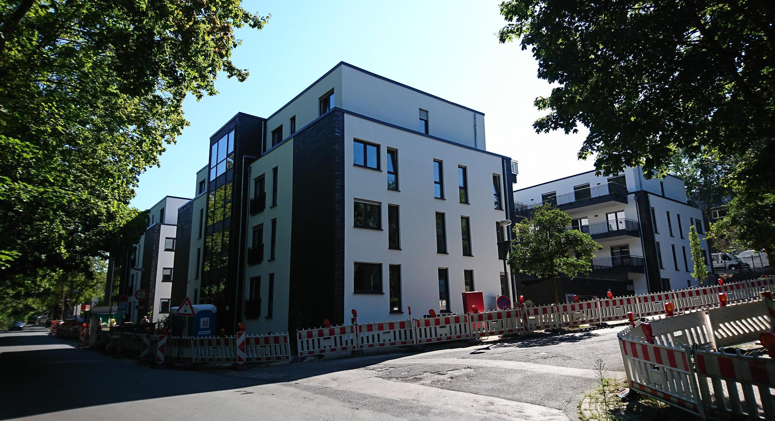 Das Bild zeigt ein mehrstöckiges neu gebautes Wohnhaus in einer Wohnsiedlung.