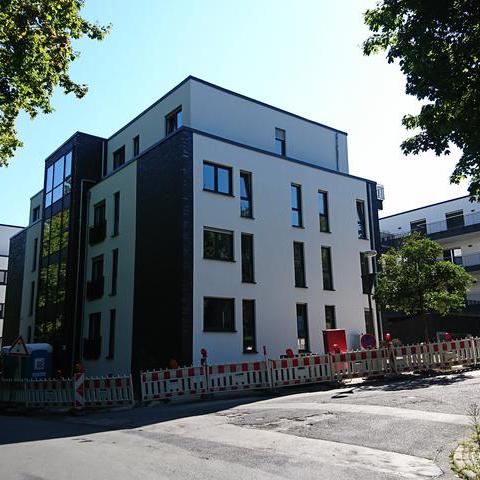 Das Bild zeigt ein mehrstöckiges neu gebautes Wohnhaus in einer Wohnsiedlung. 