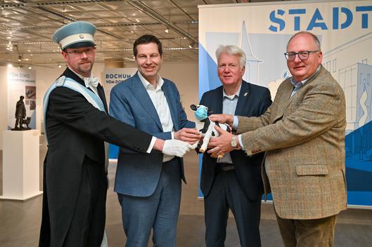 Ein während der Corona-Pandemie von Dortmunds ehemaligem Oberbürgermeister Ulrich Sierau an den Bochumer Oberbürgermeister Thomas Eiskirch übergebenes Kalb mit Mundschutz geht am 20.04.2023 im Beisein von Stefan Vahlsieck von der Maiabendgesellschaft und Dr. Kai Rawe vom Stadtarchiv in die Sammlung desselbigen über.