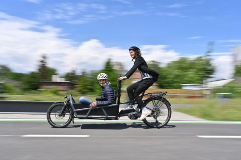 Ein Lastenrad mit Fahrerin und Mensch