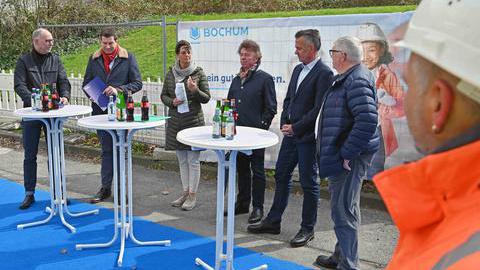 Das Bild zeigt fünf Männer und eine Frau an drei weißen Stehtischen. Sie stellen bei einem Pressetermin das Projekt "Baustellenmanagement" vor.