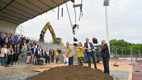 Drei Männer und eine Frau schippen mit Schaufeln Erde vom Boden als symbolischer Spatenstich für das neue Lohrheidestadion.