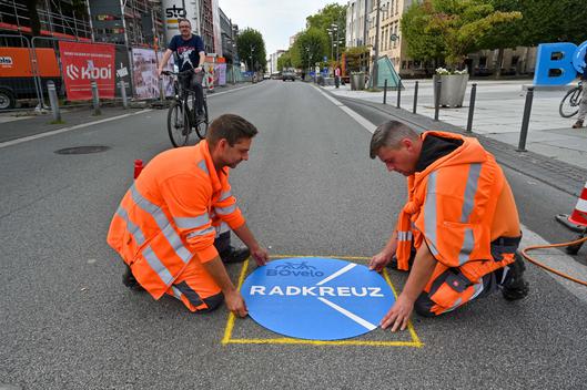 Mitarbeiter bringen Logo auf Straße an.