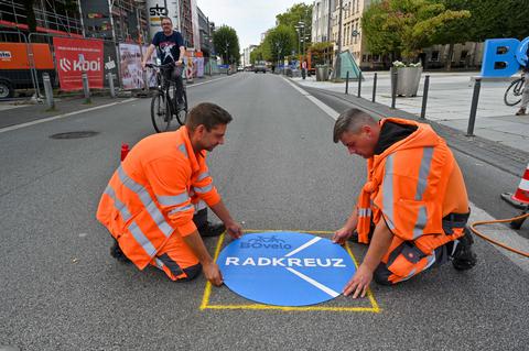 Mitarbeiter bringen Logo auf Straße an.