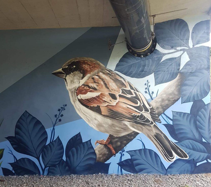 Das Bild zeigt ein Graffiti eines Vogels, der auf einem Ast sitzt.