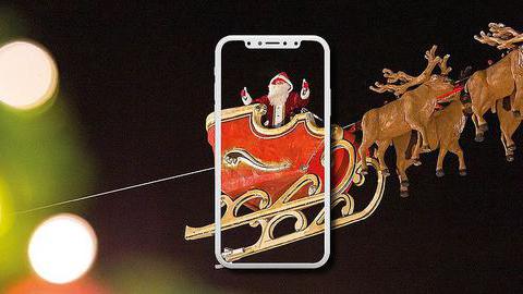 Das Bild zeigt einen Weihnachtsmann im Schlitten mit Rentieren im Bildschirm eines Smartphones.
