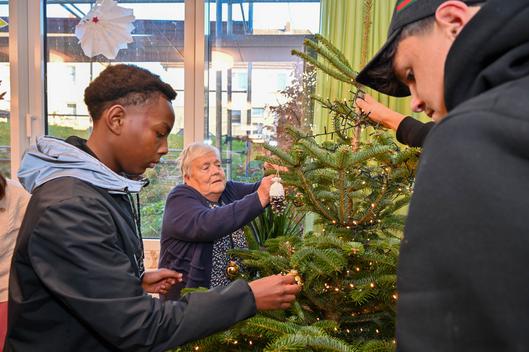 Schülerinnen und Schüler der Werner-von-Siemens-Schule sowie Gäste der Tagespflege schmücken gemeinsam einen Weihnachtsbaum