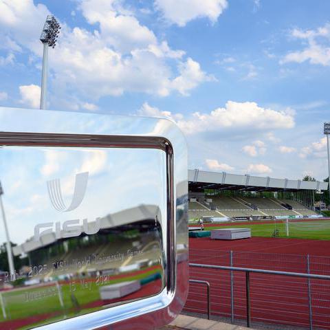 Silberne Plakette der FISU Worldgames mit eingraviertem Logo der FISU-Worldgames sowie Veranstaltungsdatum 2025 mit dem Lohrheidestadion im Hintergrund