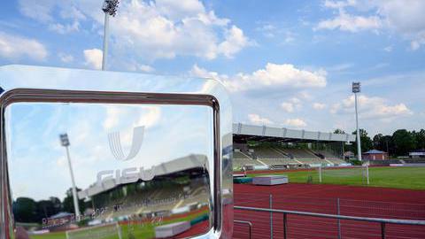 Silberne Plakette der FISU Worldgames mit eingraviertem Logo der FISU-Worldgames sowie Veranstaltungsdatum 2025 mit dem Lohrheidestadion im Hintergrund