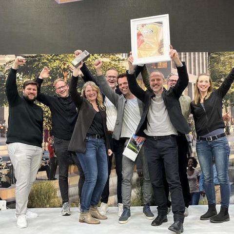 Eine Gruppe von Menschen mit dem Polis-Award und der gerahmten Urkunde (Mitte: Dr. Britta Freis, Leiterin Projektbüro Haus des Wissens)