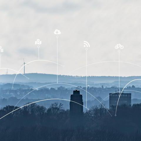 Skyline-Aufnahme von Bochum in der Dämmerung. Links ist das Excenterhaus zu sehen, mittig im Vordergrund der Bismarkturm und die Bäume des Stadtparks