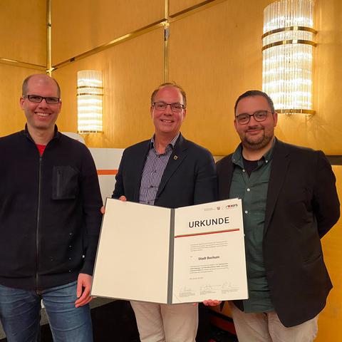 Bürgermeister Dr. Sascha Dewender (Mitte), Raphael Dittert (rechts), Vorsitzender des Ausschusses für Mobilität und Infrastruktur, und Matthias Olschowy (links), Nahmobilitätsbeauftragter nehmen im Namen der Stadt Bochum die Urkunde entgegen.