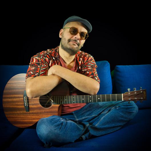 Ein Bild von Alex de Macedo zusammen mit seiner Gitarre