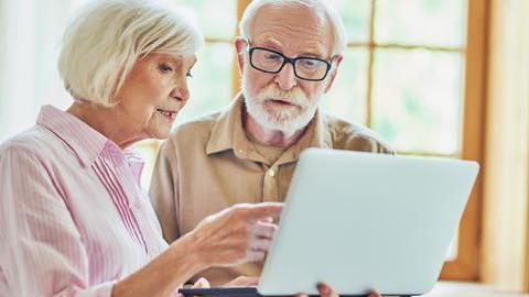 Ein älteres Ehepaar schaut gemeinsam auf einen Laptop.