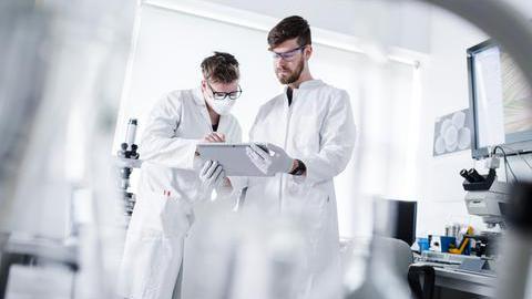 Das Bild zeigt zwei junge Männer in weißen Kitteln in einem Labor.