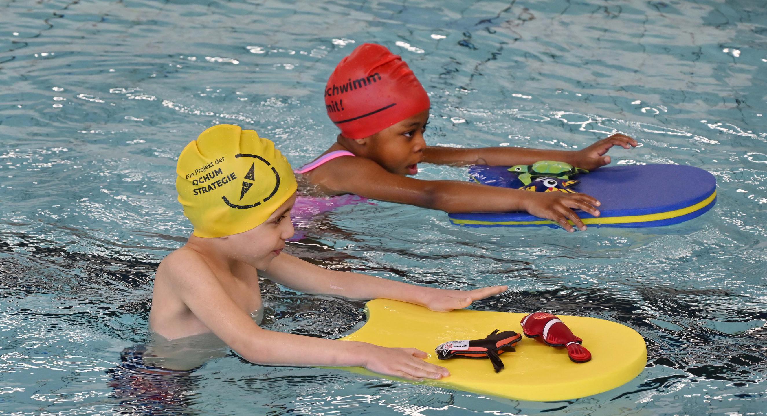 Zwei jungen, die mit Schwimmbrett im Wasser Schwimmen lernen.